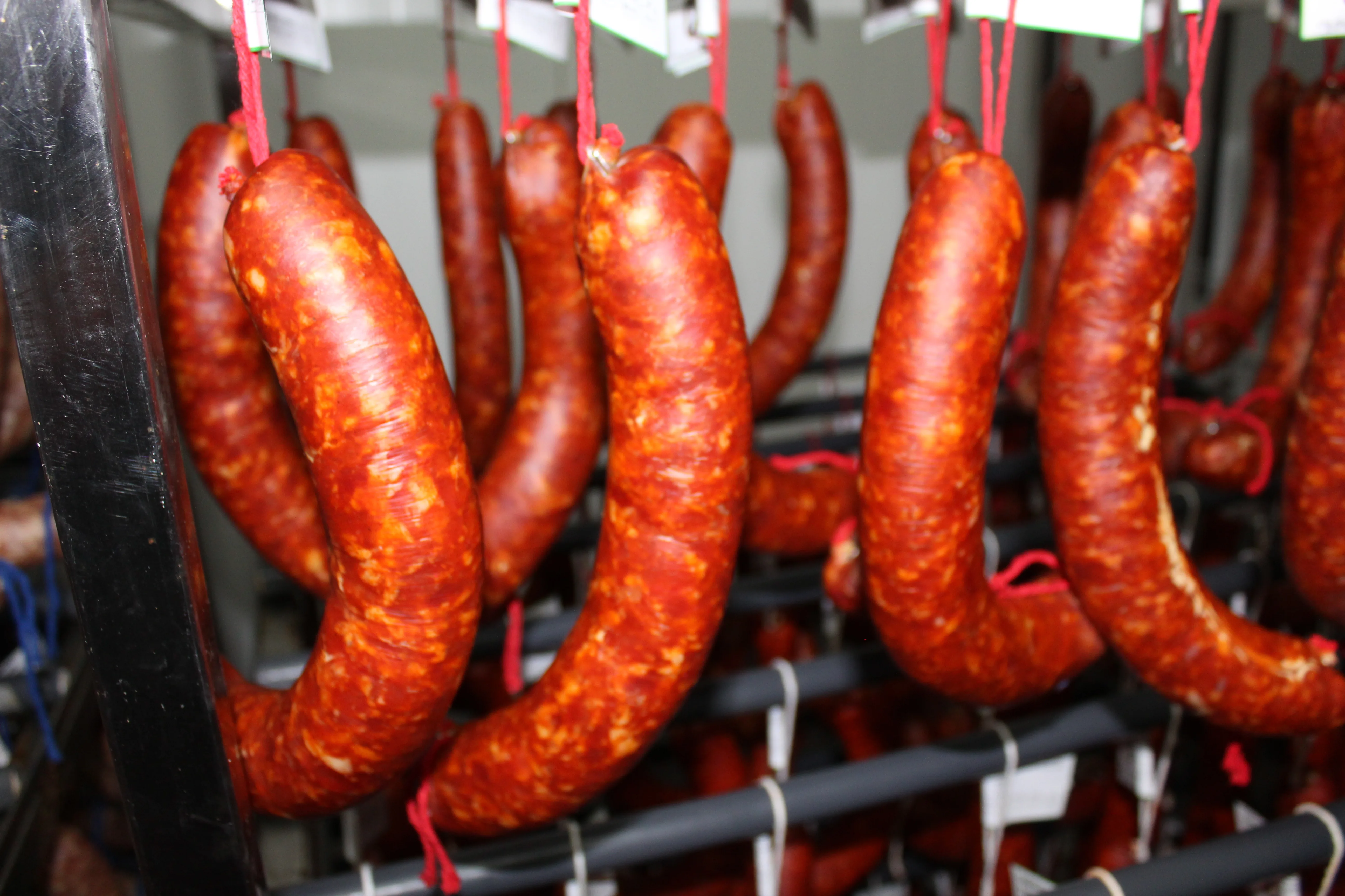 Chorizos artesanos rojos colgando en proceso de curación fábrica Cárnicas Pozo Hondo