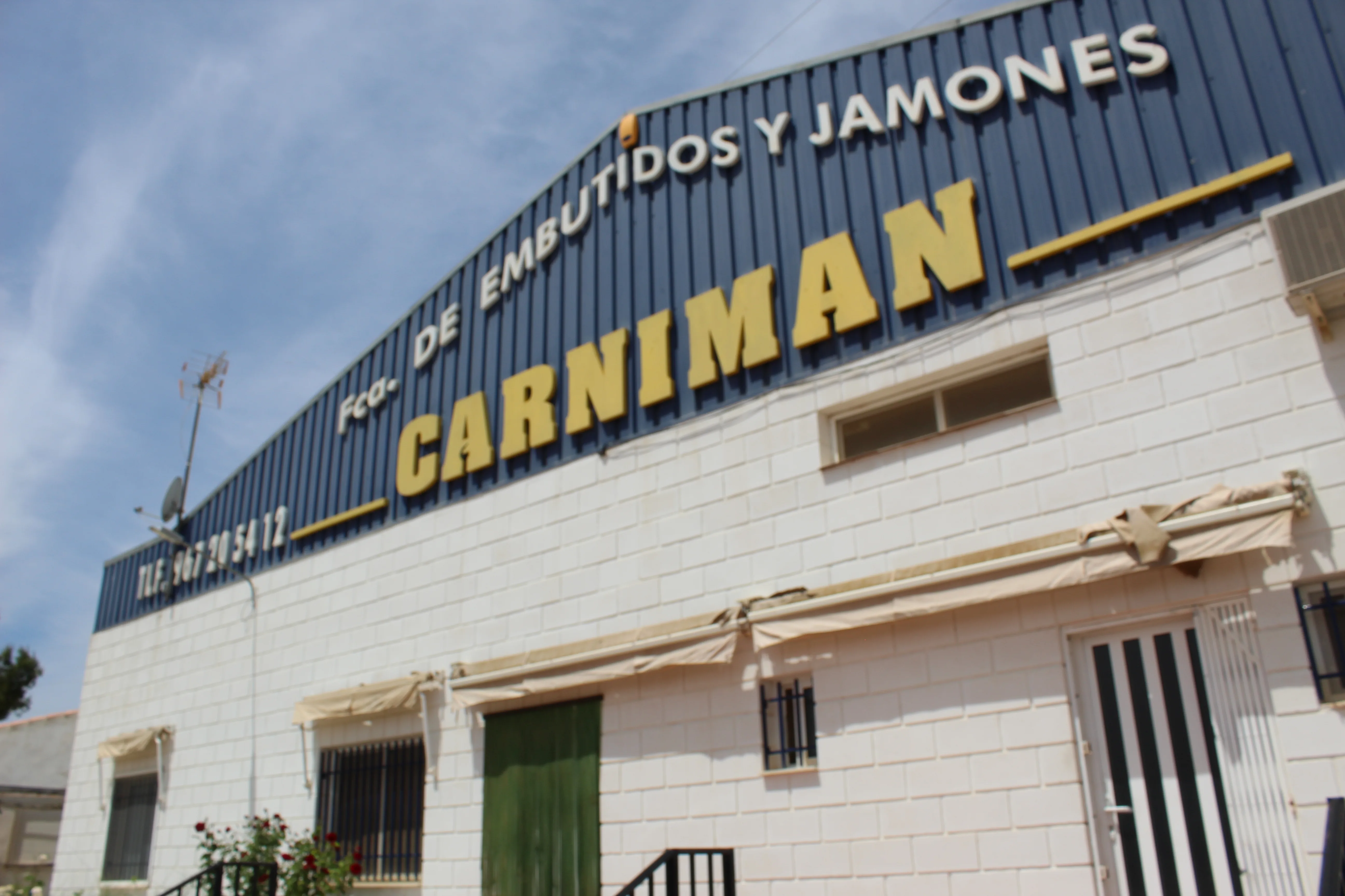 Fachada de la fábrica de embutidos Cárnicas Pozo Hondo en Pozohondo con el gran rótulo amarillo
