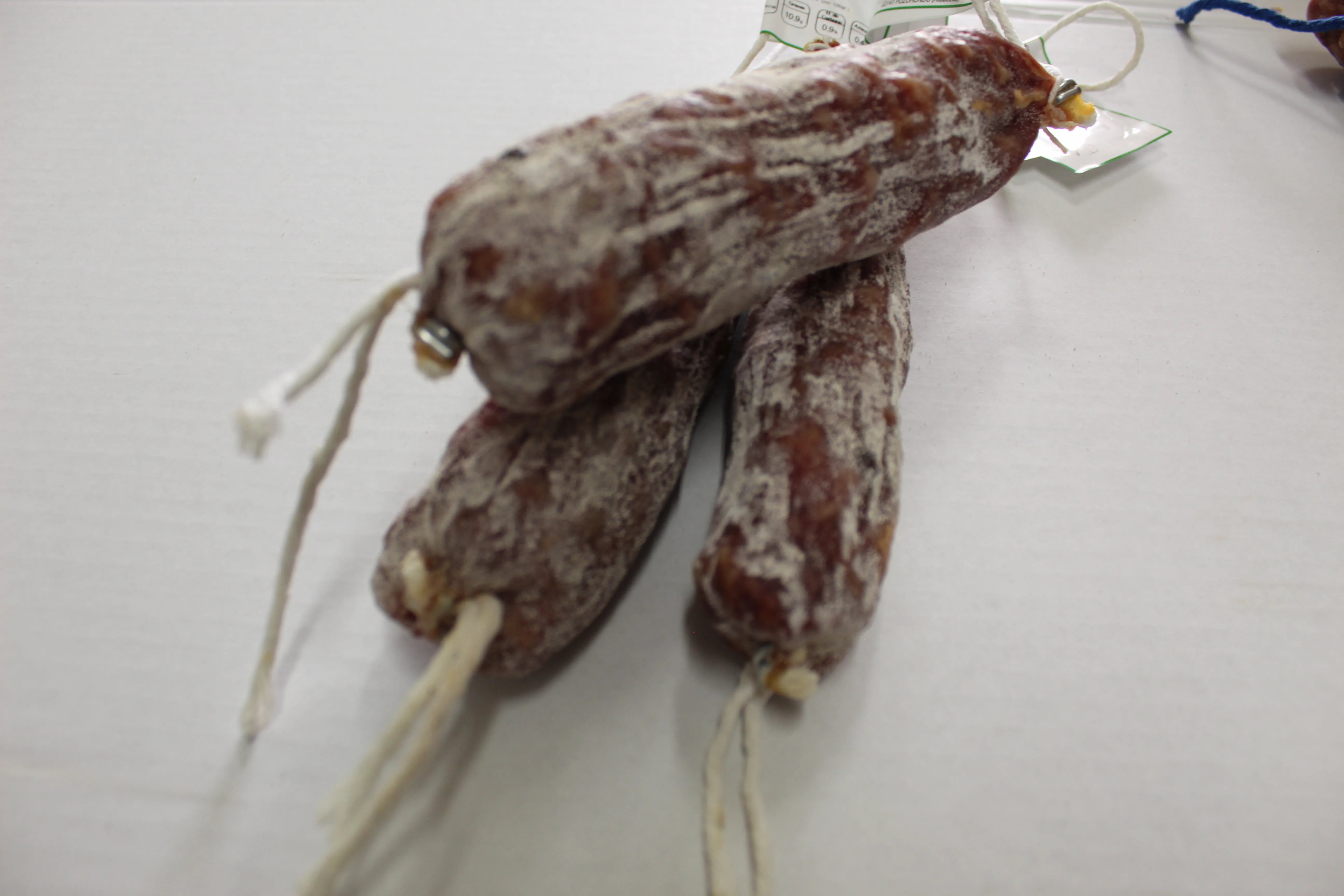 Fuet y salchichón curado artesano Cárnicas Pozo Hondo sobre superficie blanca